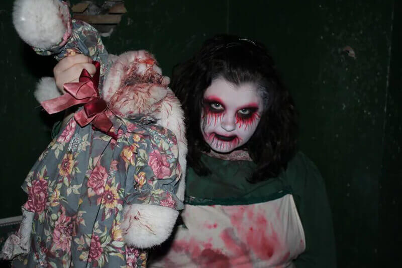 Frightmare Manor haunted house in Tennessee horror faced girl holding a creepy doll